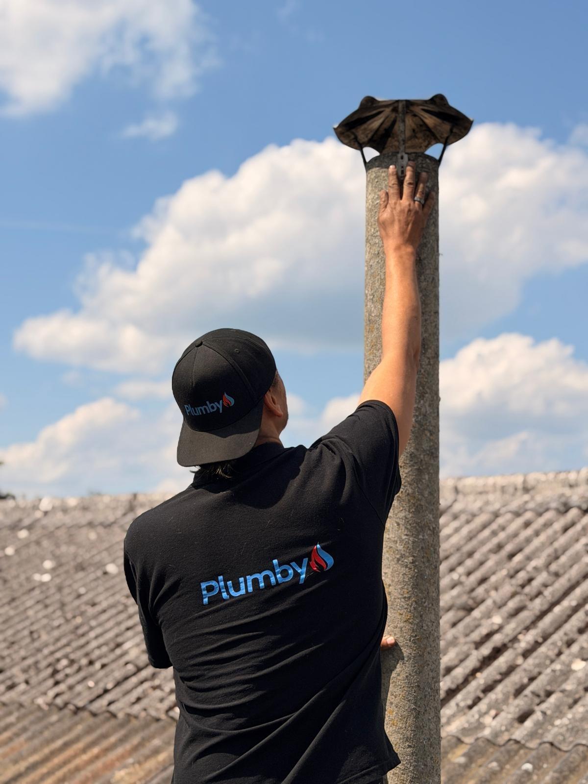Schornsteinreinigung auf dem Dach durch einen Plumby-Techniker